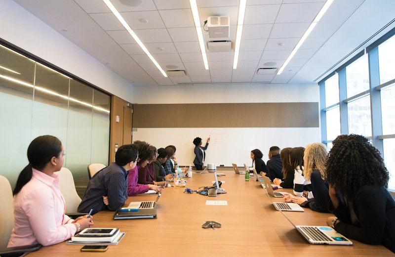 Equipe reunida em sala de reunião durante treinamento com quadro branco